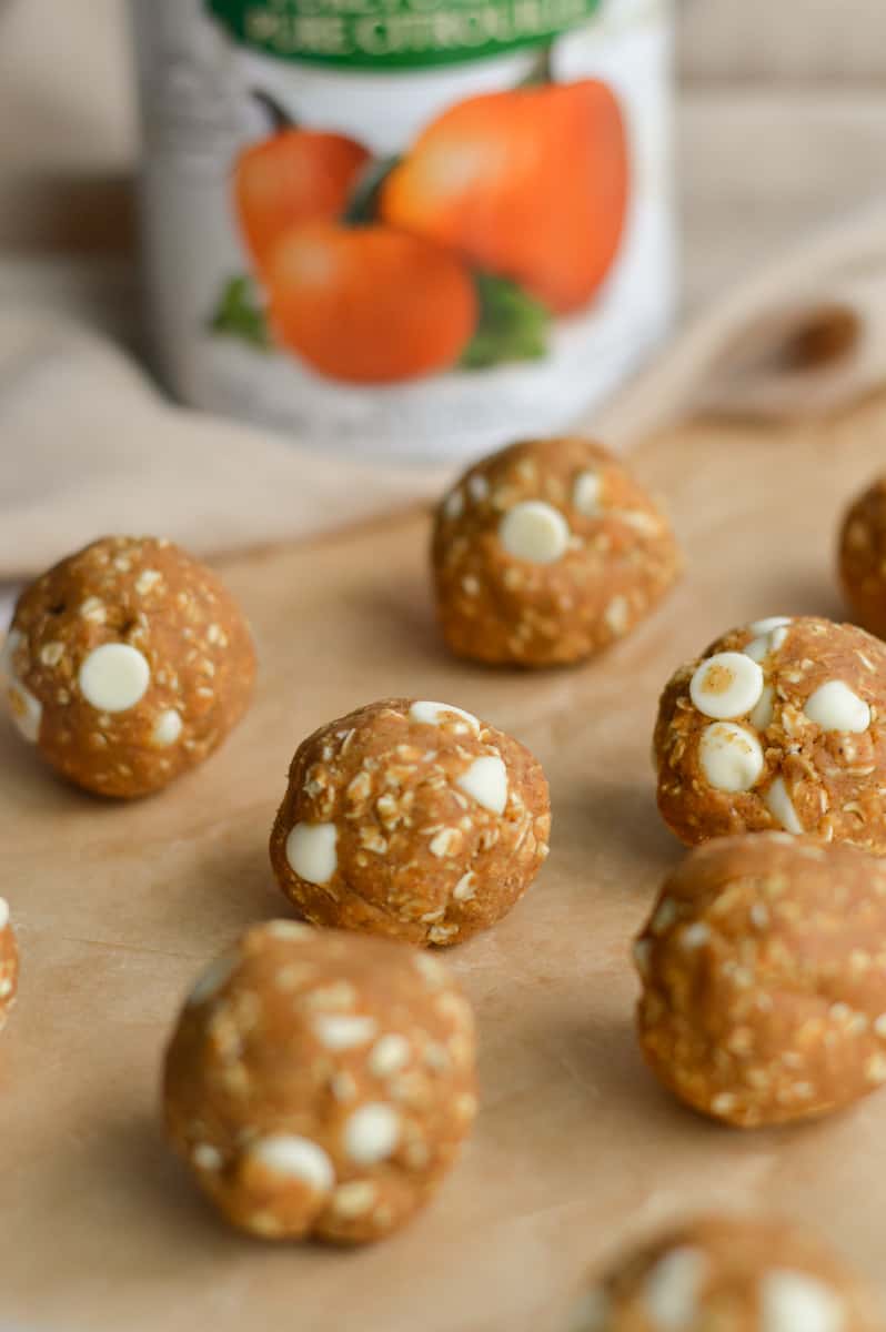 Rolling out pumpkin protein balls on a tray.