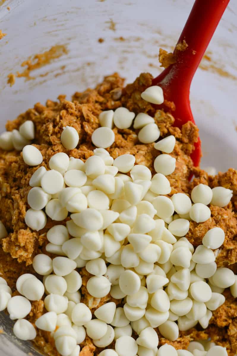 Adding white chocolate chips to protein ball mixture.