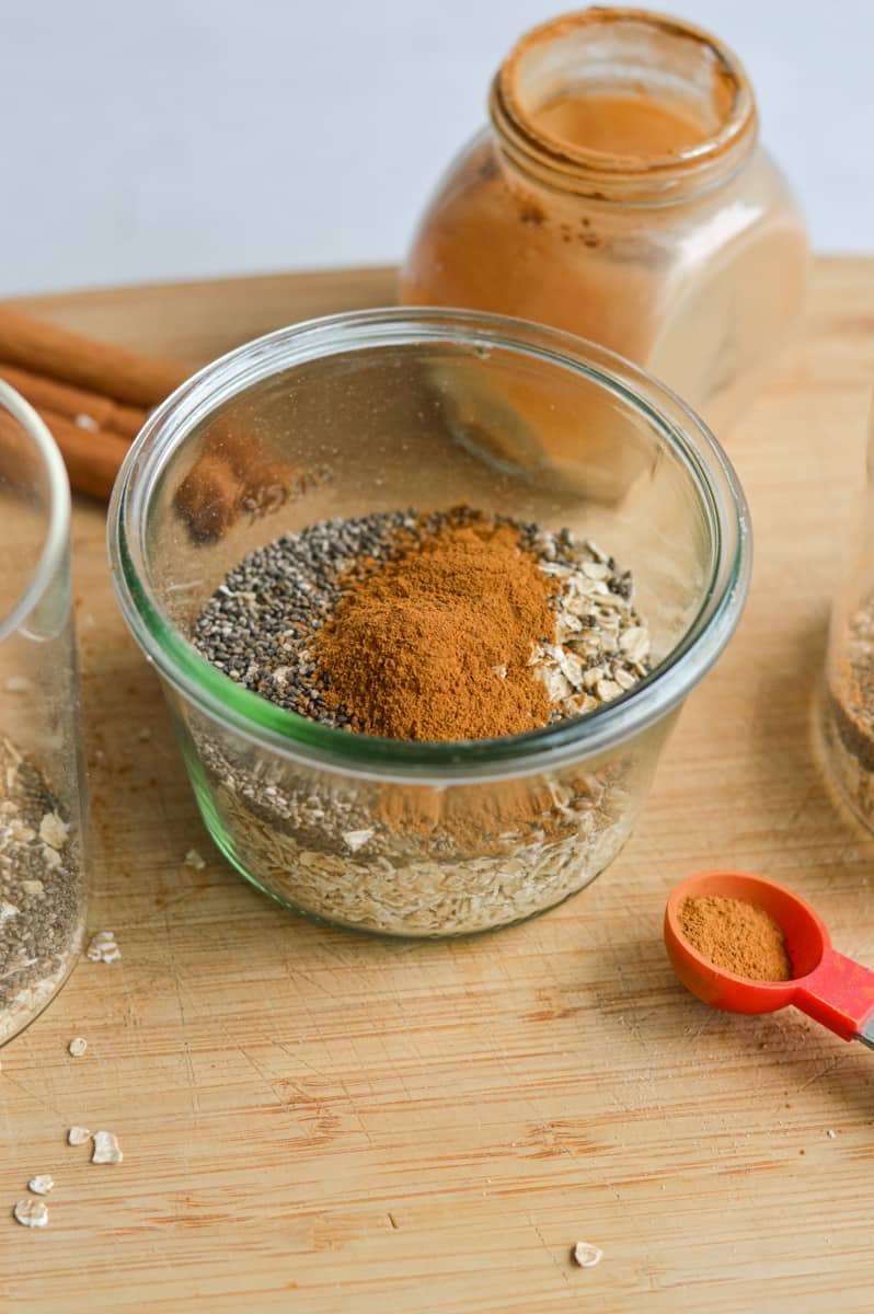 Adding oats, chia seeds, vanilla protein powder, cinnamon and salt to a jar.
