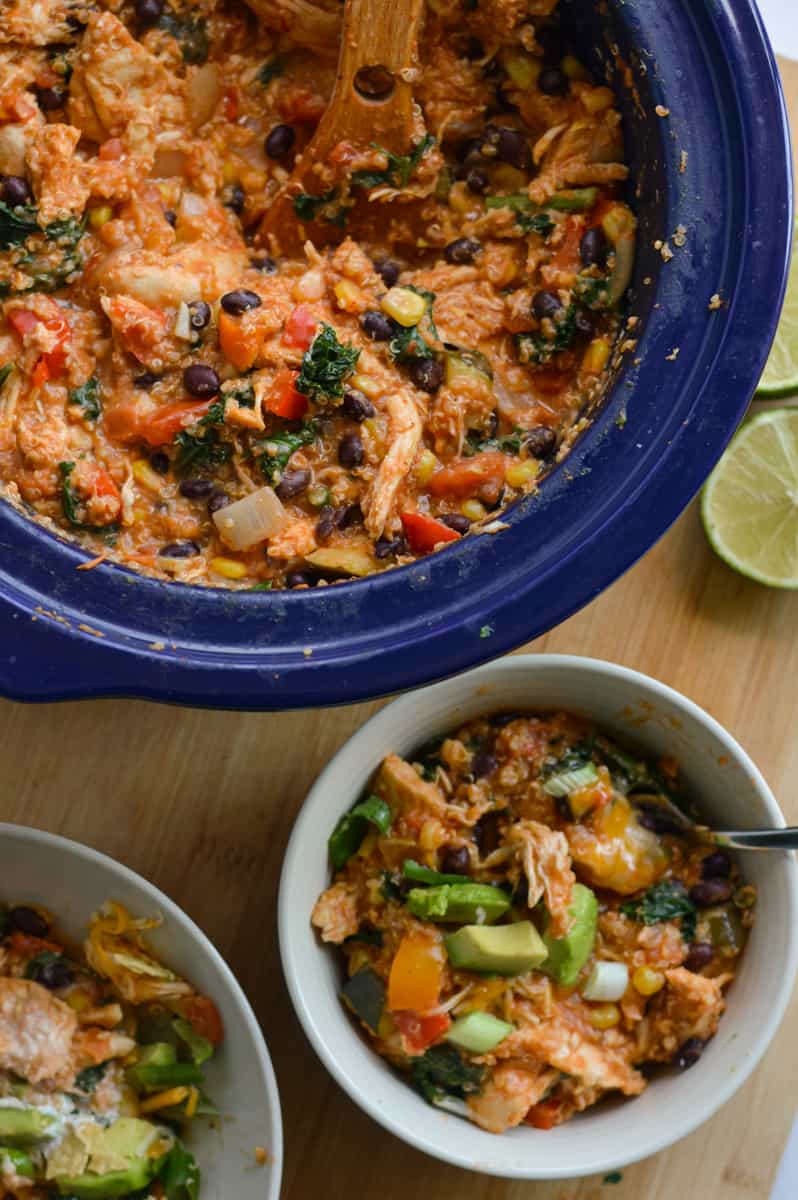 Serving southwest chicken bowls from a slow cooker, topped with avocado and green onion.