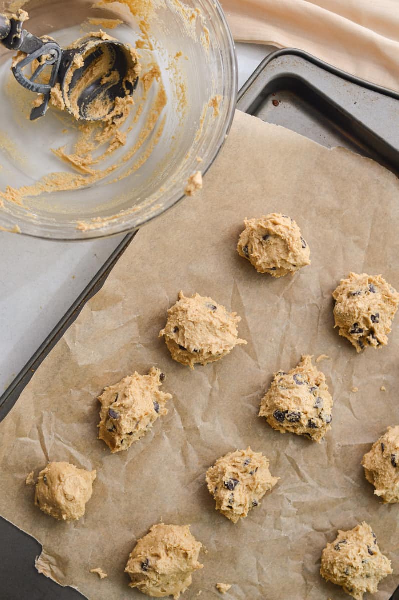 Scooping out oat flour cookie dough onto a baking tray.