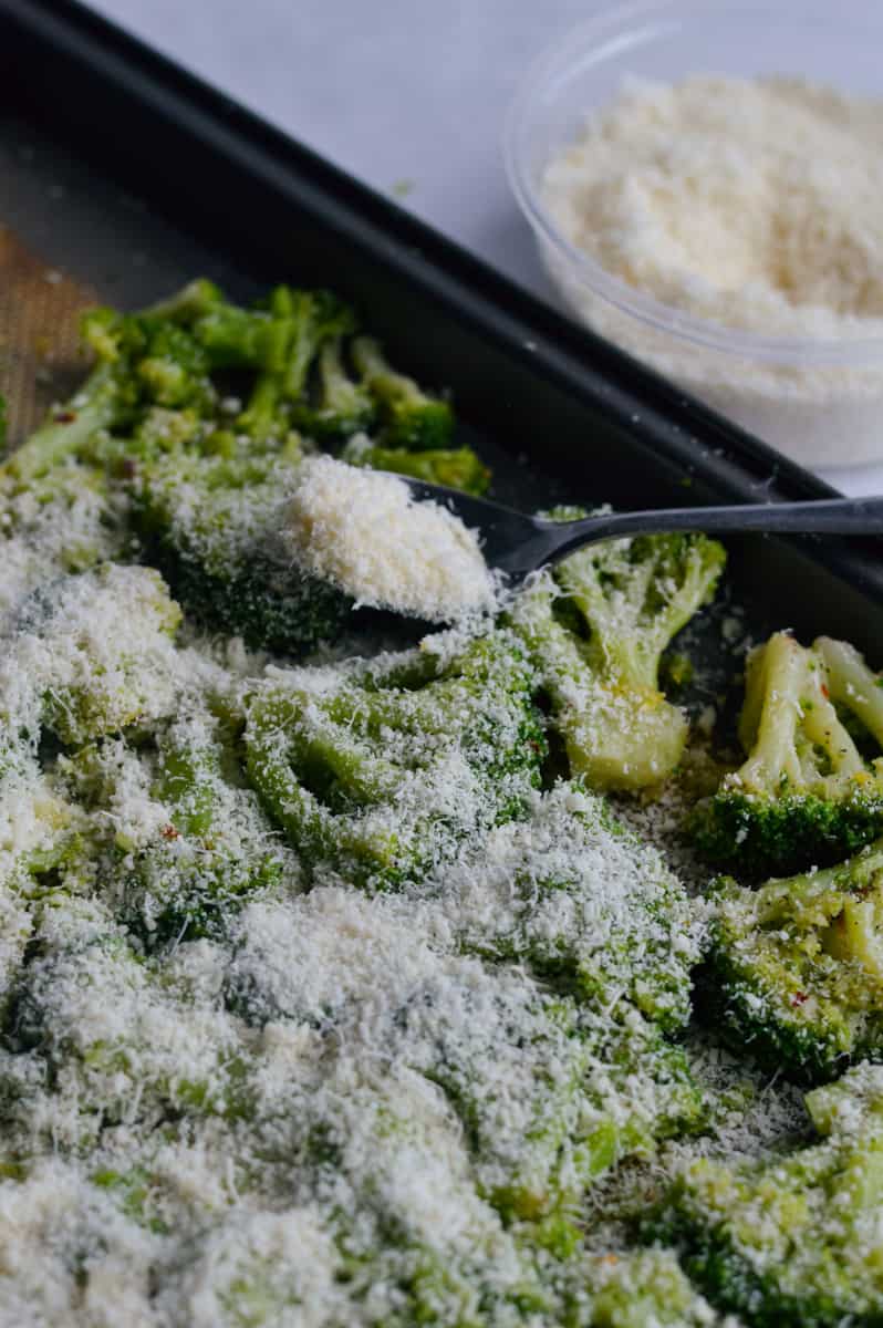Sprinkling parmesan on smashed broccoli.