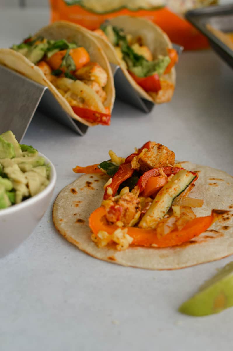 Assembling tofu fajitas and topping with avocado.