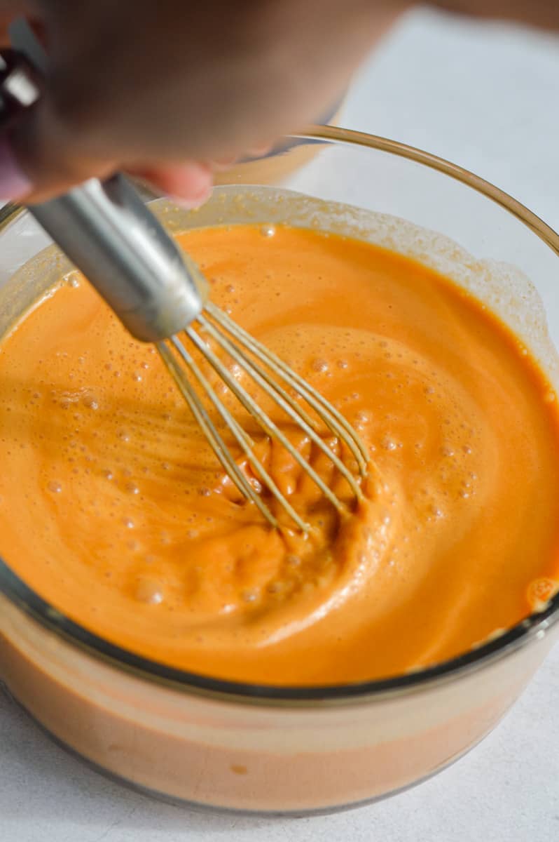 Whisking red curry paste, soy sauce, chicken broth, rice vinegar, peanut butter,  and honey to make peanut sauce. 
