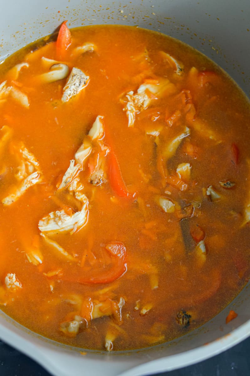 Adding chicken and coconut milk to the soup.