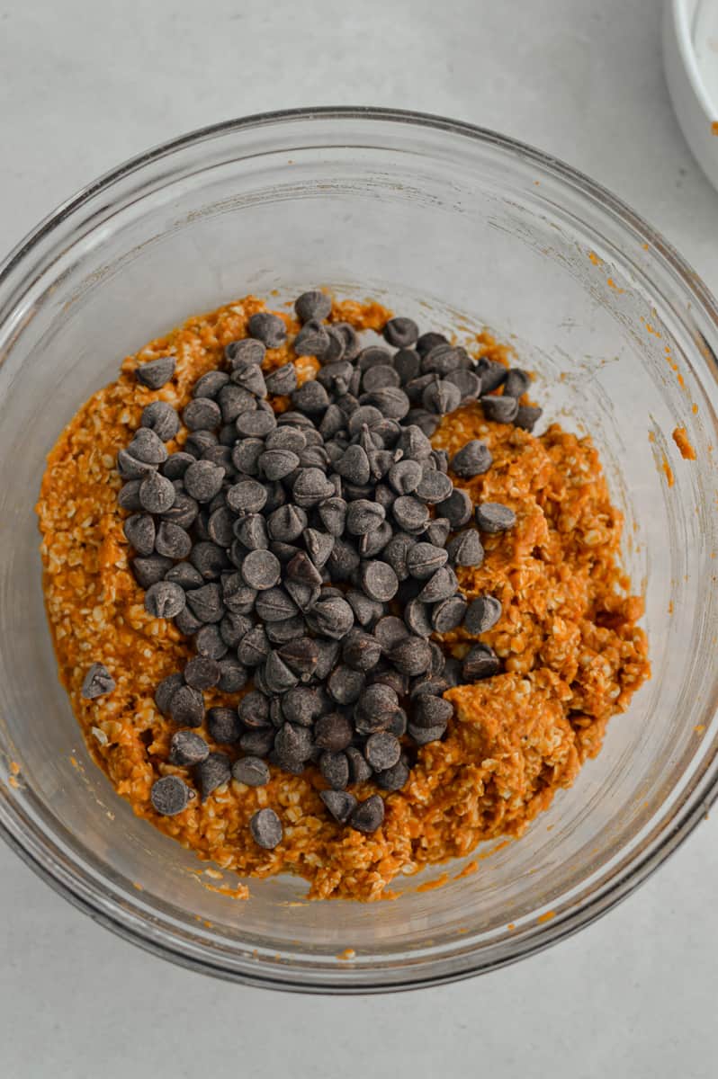Adding chocolate chips to pumpkin cookie dough.