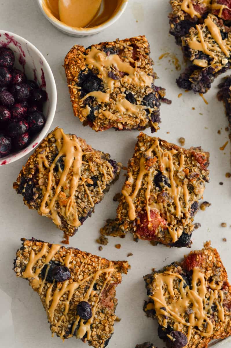 Birds eye of no banana baked oat bars with berries and a peanut butter drizzle.