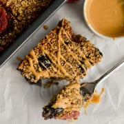 Eating baked oats without banana with a fork, drizzling peanut butter on top.
