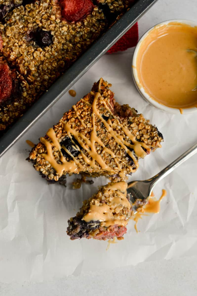 Eating baked oats without banana with a fork, drizzling peanut butter on top.
