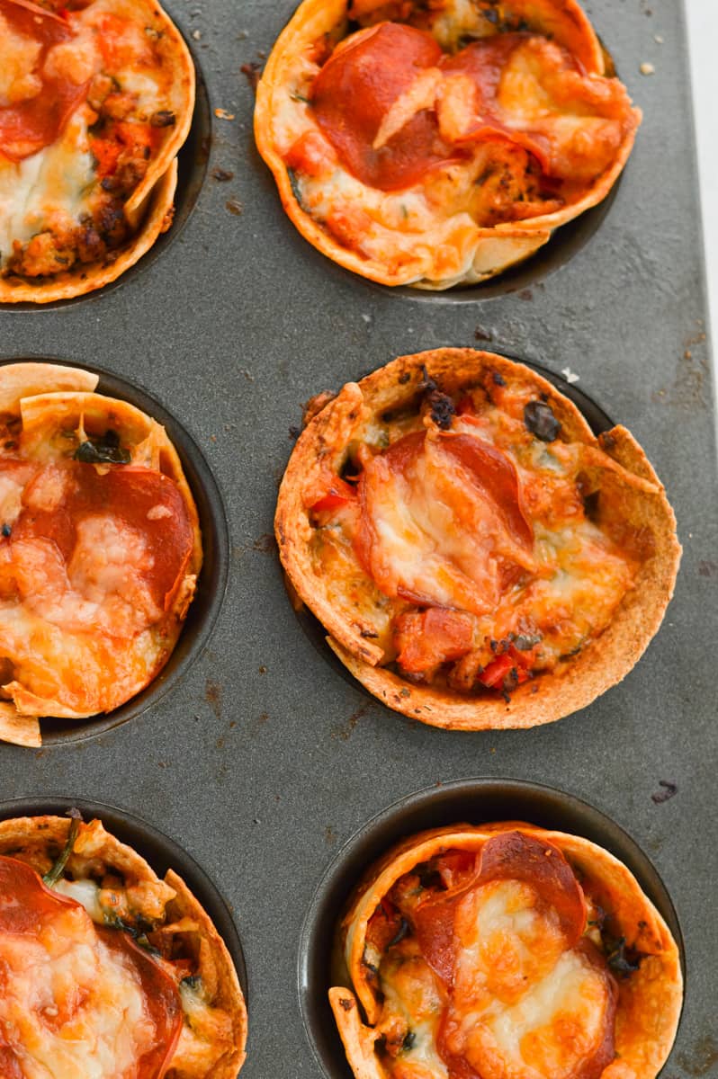 Close up of baked pizza cups in a muffin tin.