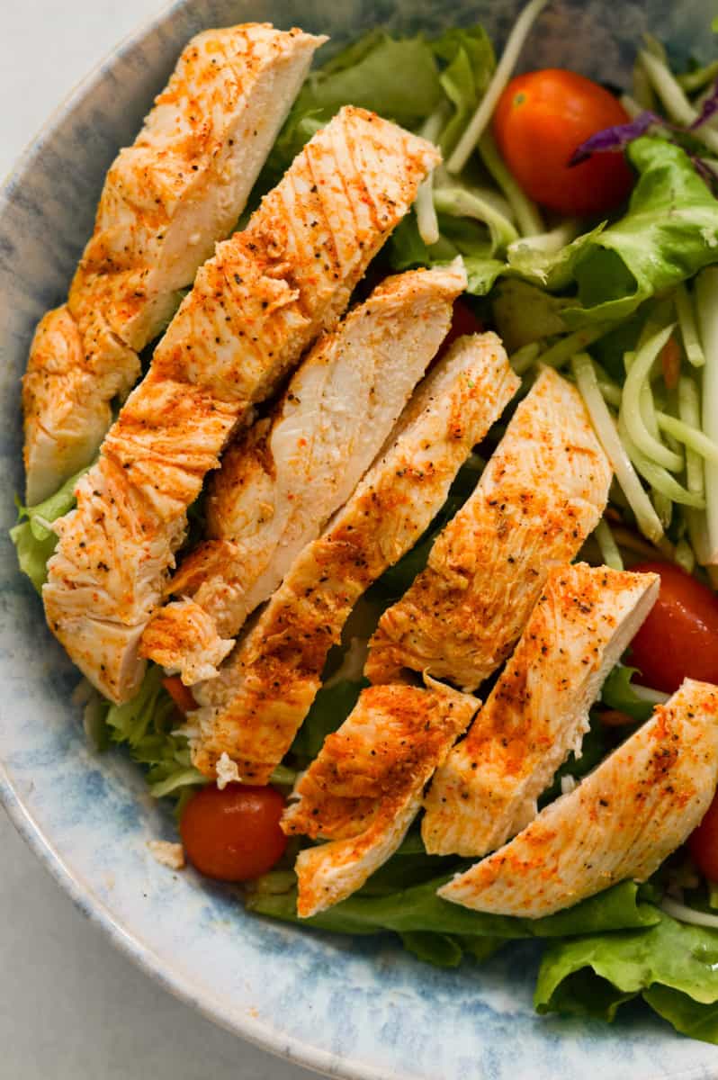Baked thin sliced chicken breast on a salad.