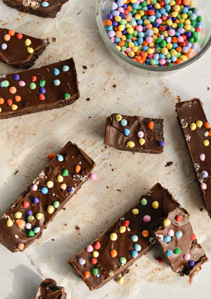 Birds eye view of chocolate brownie nut free protein bars with a bowl of rainbow sprinkles.