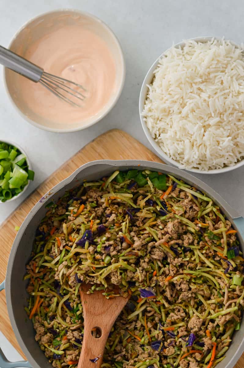 Building egg roll bowls with rice and sriracha mayo.