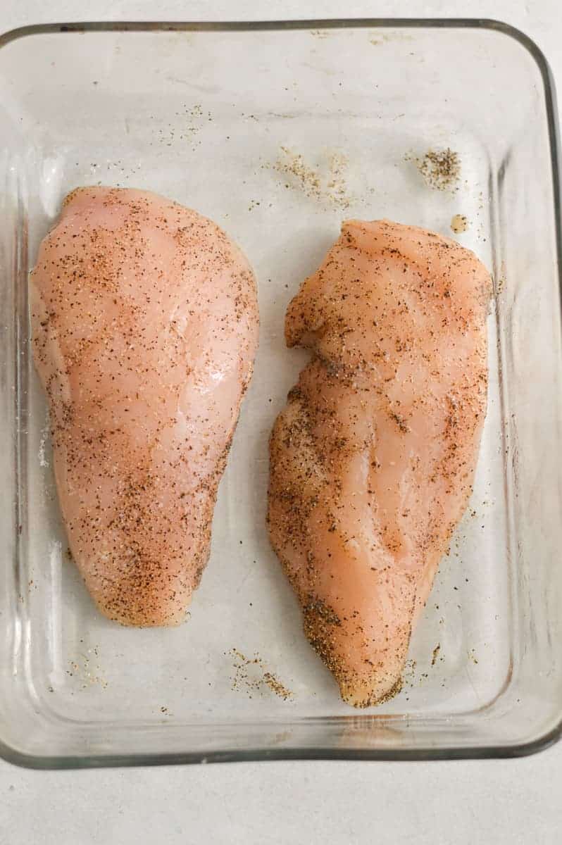 Coating chicken breast in spices and oil. 