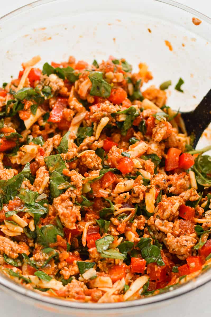 Mixing cooked turkey with veggies.