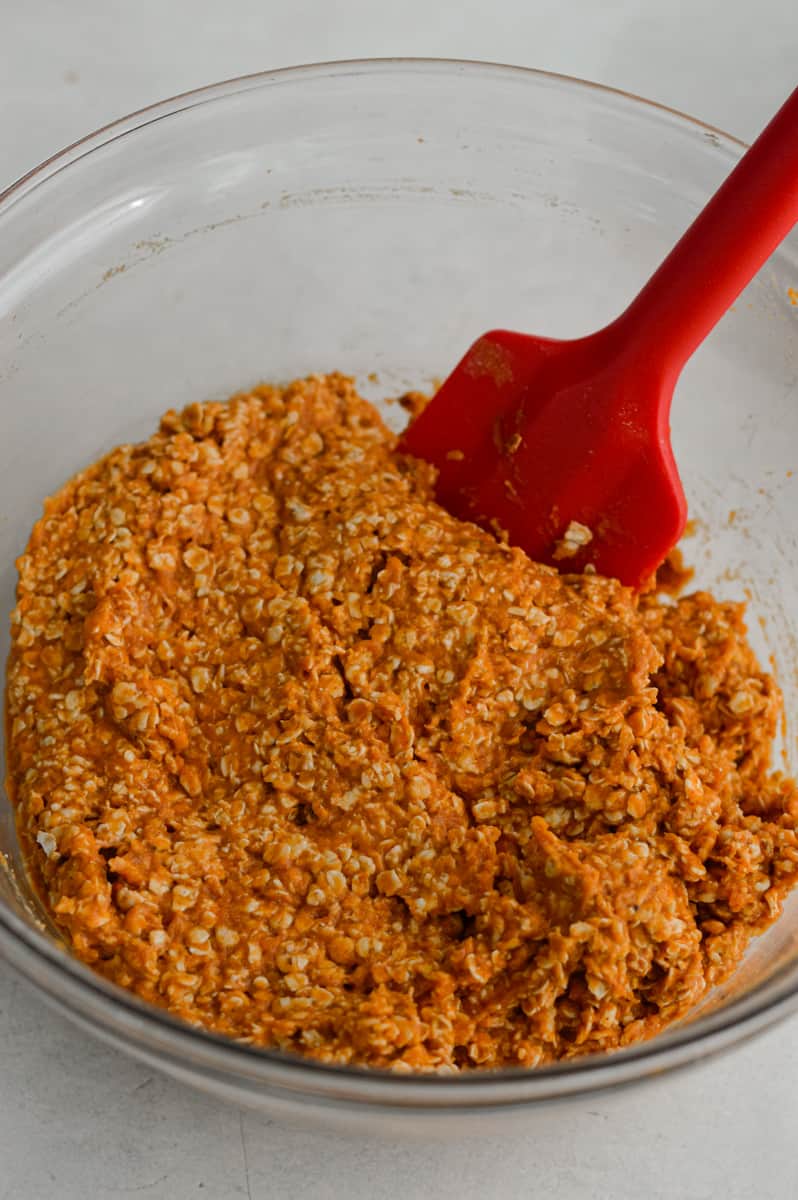Mixing wet and dry ingredients to form orange pumpkin cookie dough.
