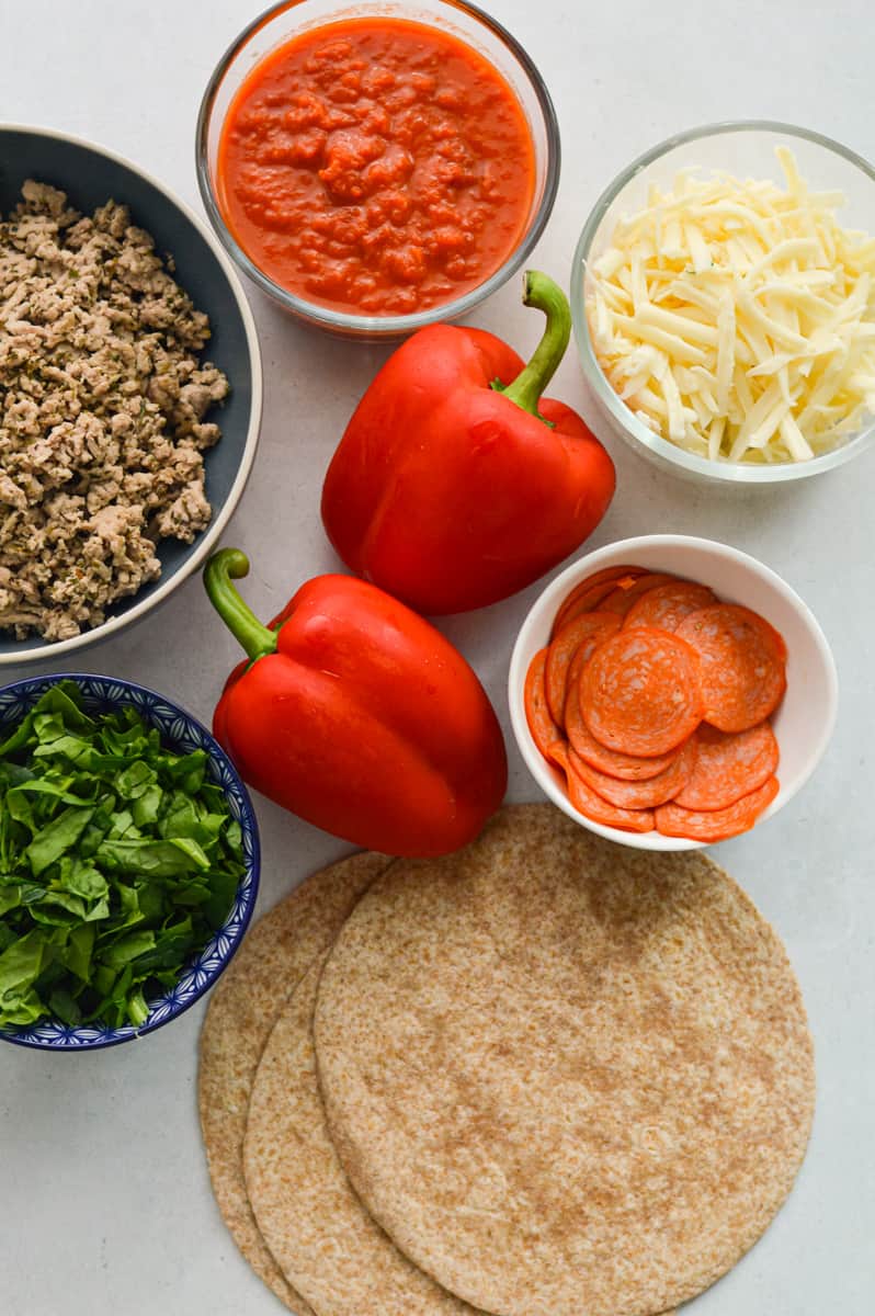 Ingredients including veggies, pizza sauce, whole wheat tortillas, ground turkey, cheese and pepperoni.