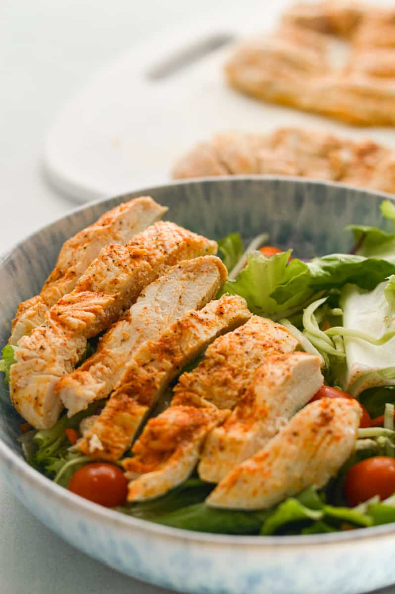 Salad with baked thin sliced chicken breast.