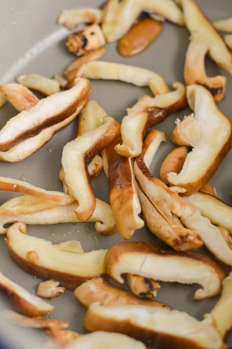 Sauteeing shiitake mushrooms in a pan.