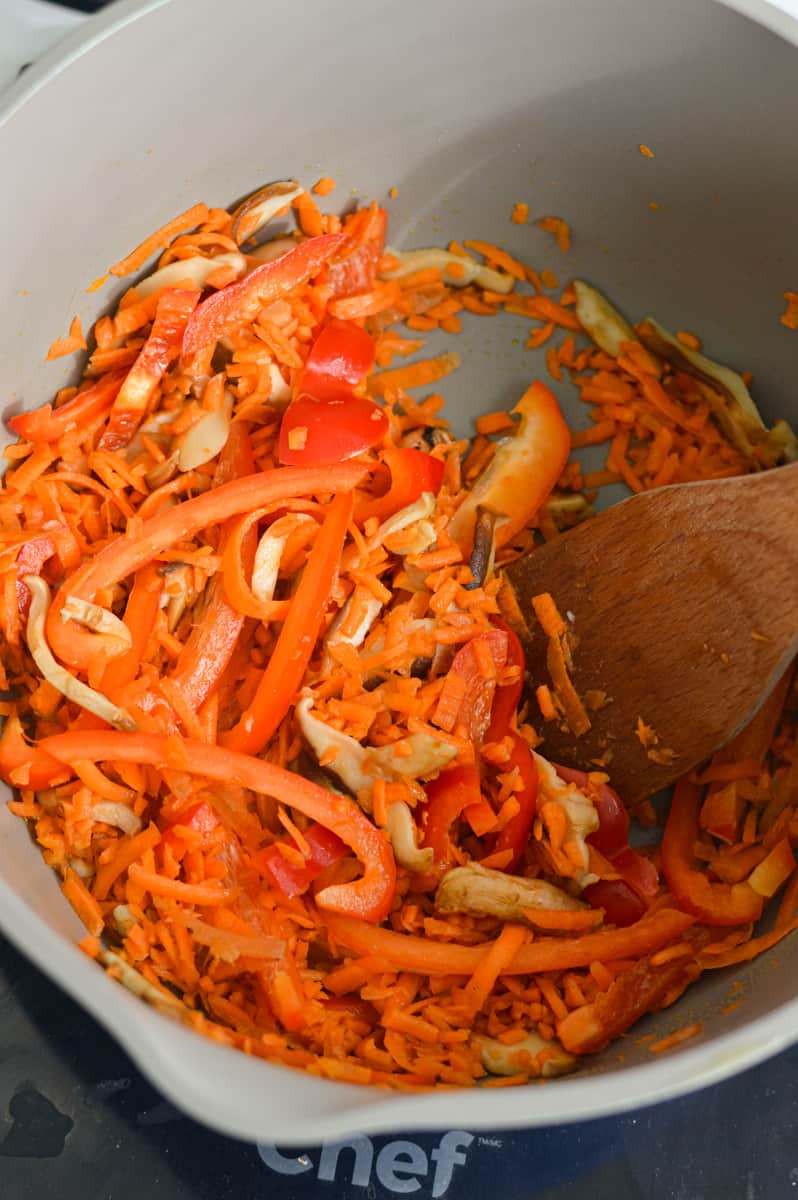 Sauteeing shredded carrots and red bell peppers.