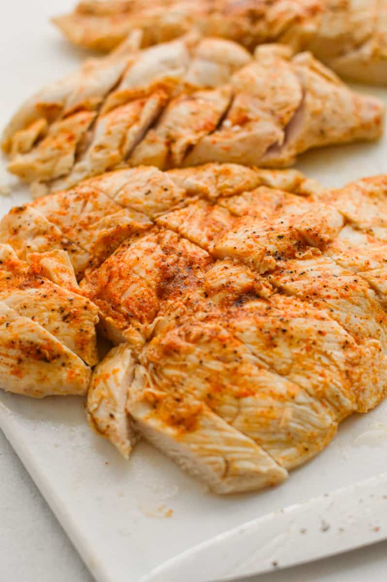 Thinly sliced chicken breast on a cutting board.