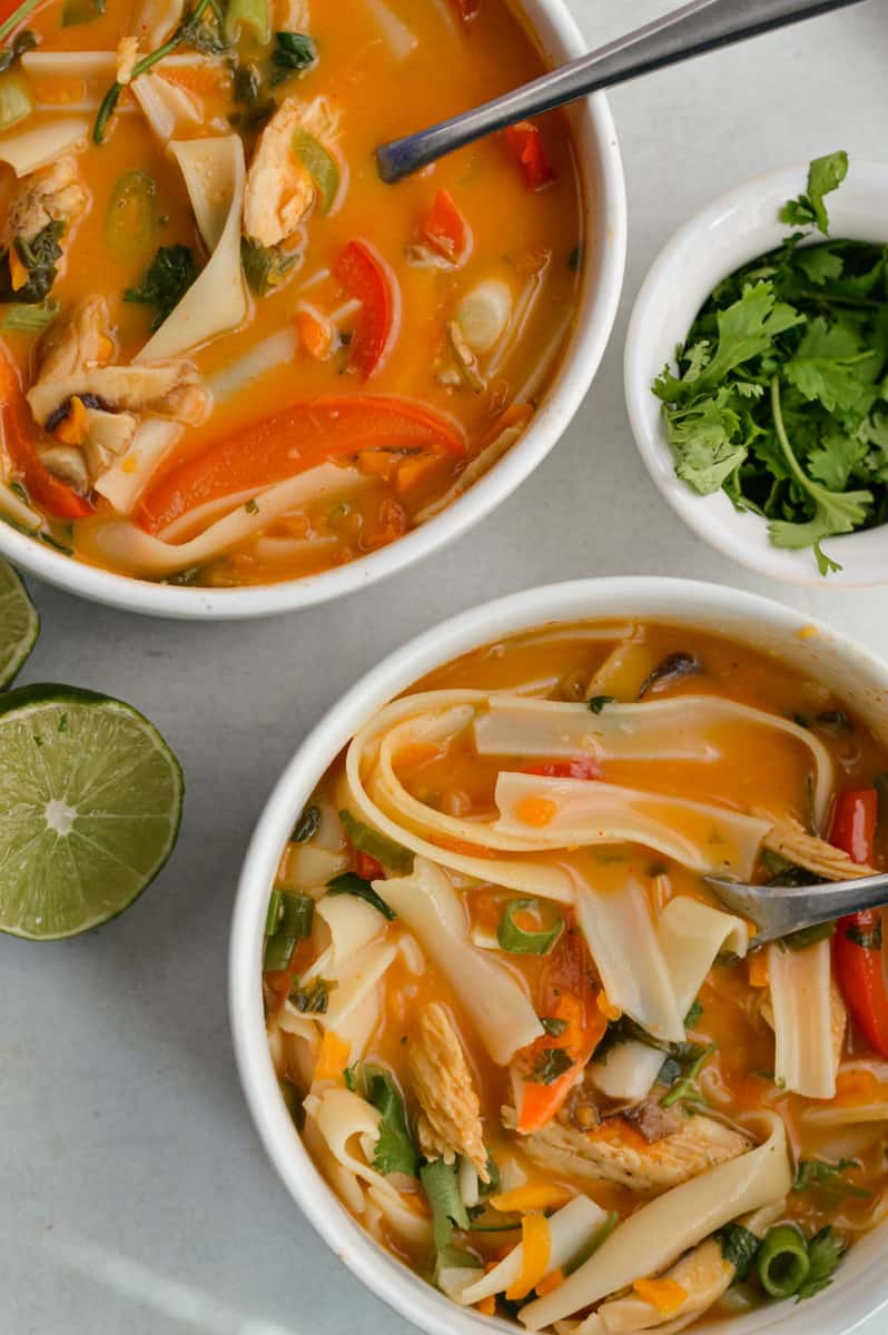 Two bowls of Panera Thai chicken soup, served with lime and cilantro.