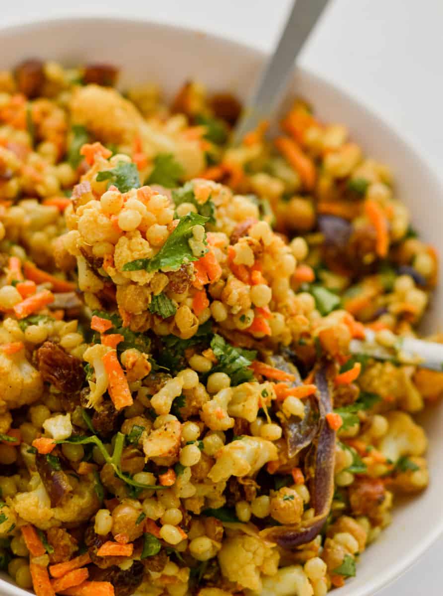 Close up of curried couscous salad with cauliflower, carrots, raisins and almonds.