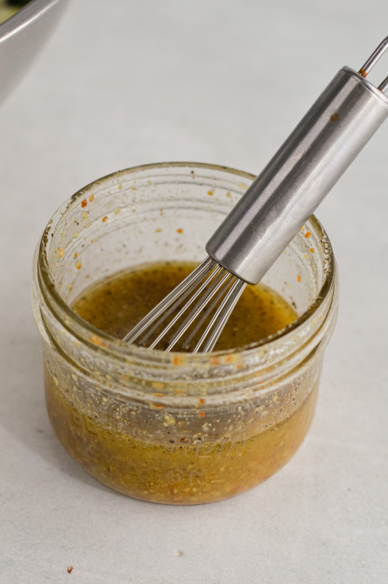 Whisking dijon apple cider vinaigrette in jar.