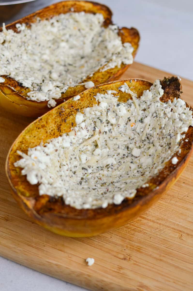 Spreading cheesy topping onto cooked spaghetti squash.