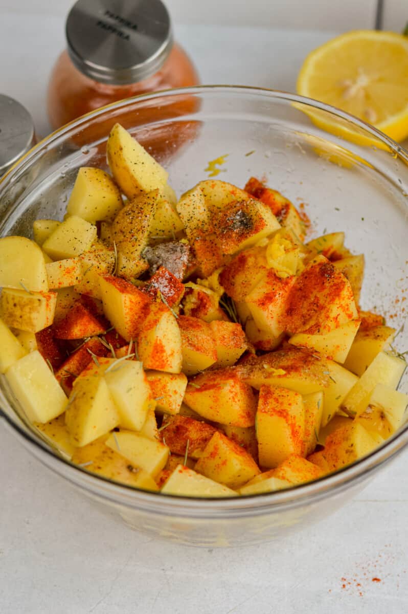 Tossing diced potatoes with olive oil and spices.