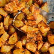 Close up of crispy air fryer diced potatoes in a bowl with a spoon.