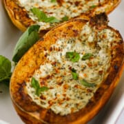 Two halves of air fryer spaghetti squash with a cheesy topping and basil.