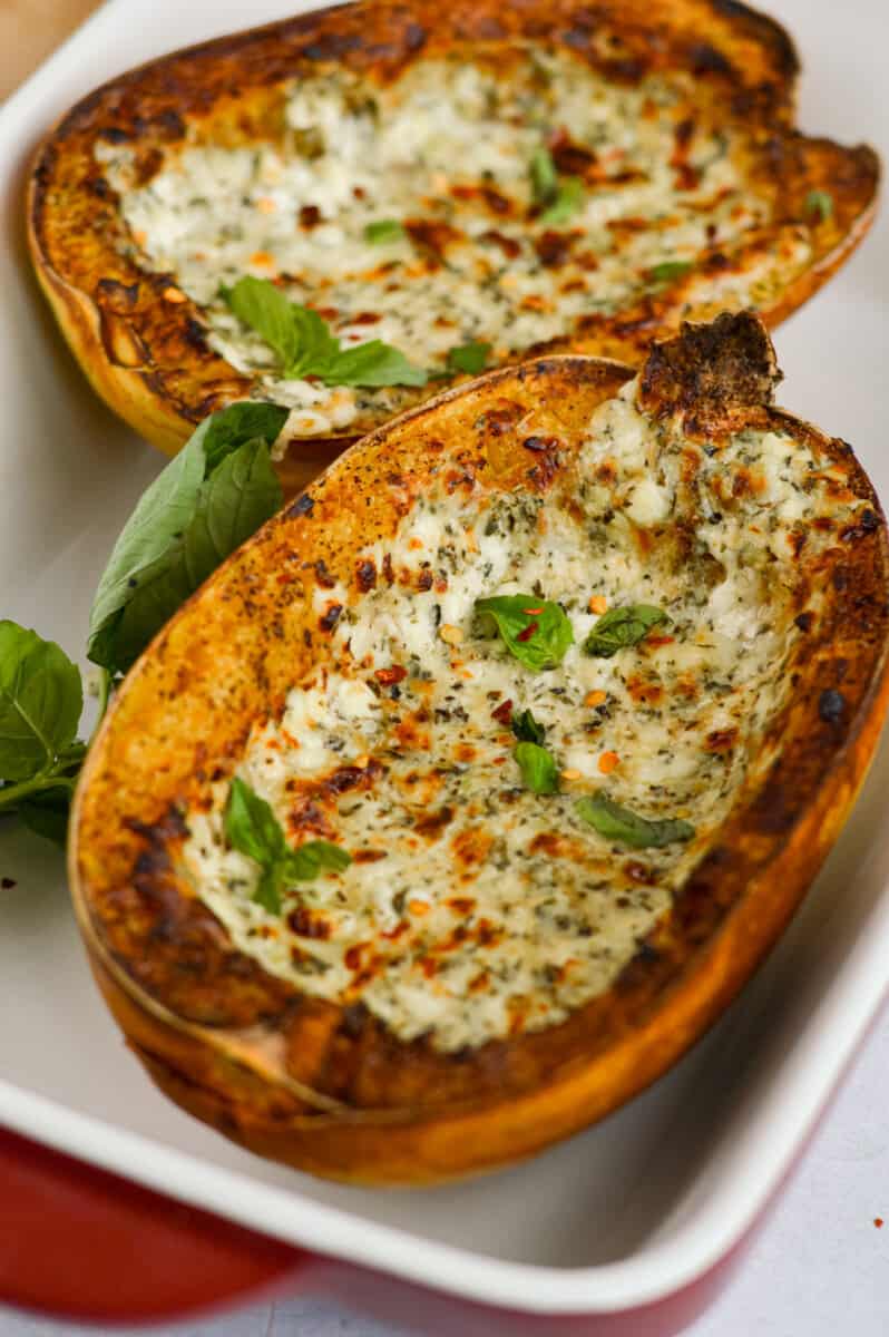 Two halves of air fryer spaghetti squash with a cheesy topping and basil.
