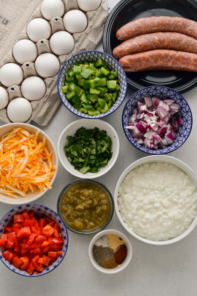 Ingredients including eggs, cilantro, cottage cheese, shredded cheese, onion, peppers, green chili, chroizo and seasoning.