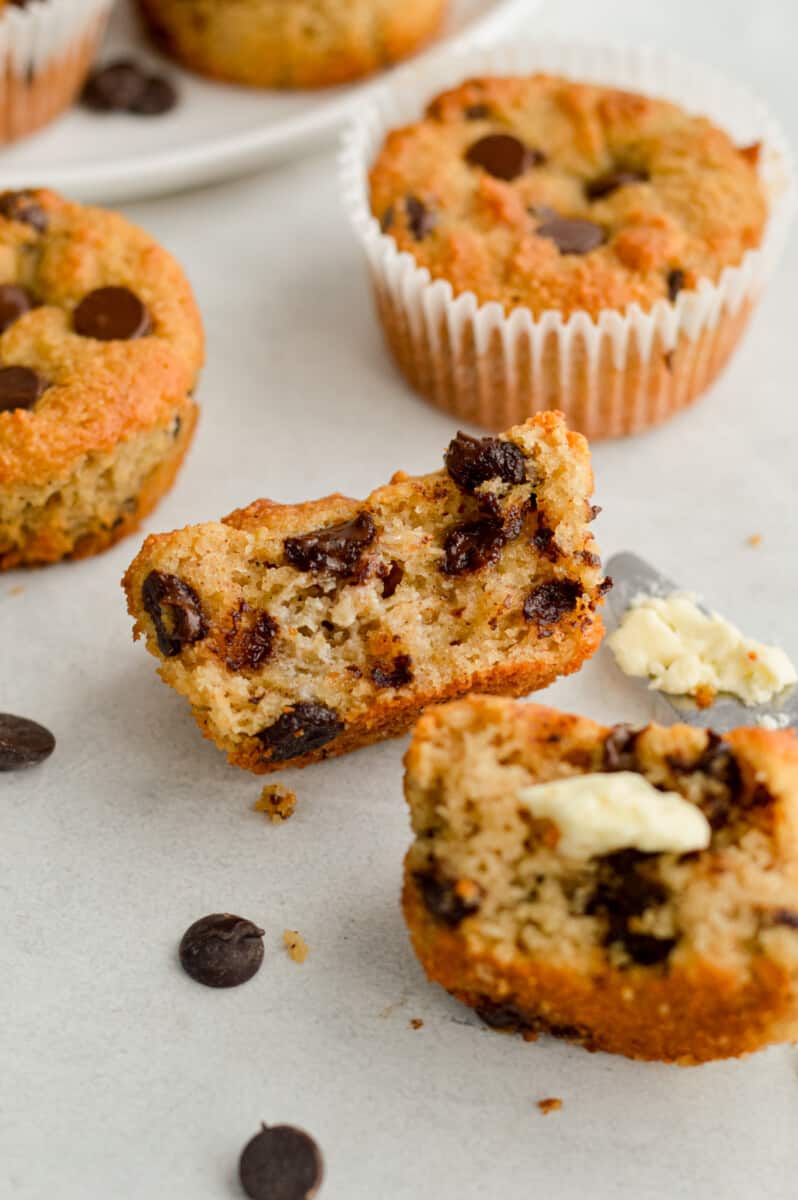Two halves of a gluten free chocolate chip muffin topped with butter.