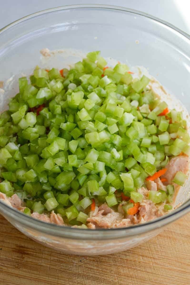 Adding diced celery into tuna salad.