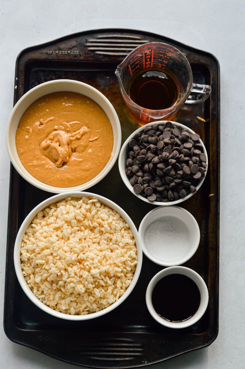 Ingredients including rice krispies, peanut butter, chocolate chips, maple syrup, coconut oil and salt.