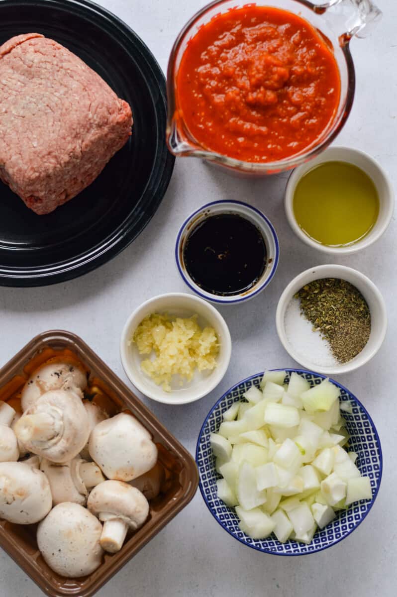 Ingredients including ground beef, mushrooms, tomato sauce, olive oil, garlic, onions, spices and balsamic vinegar.