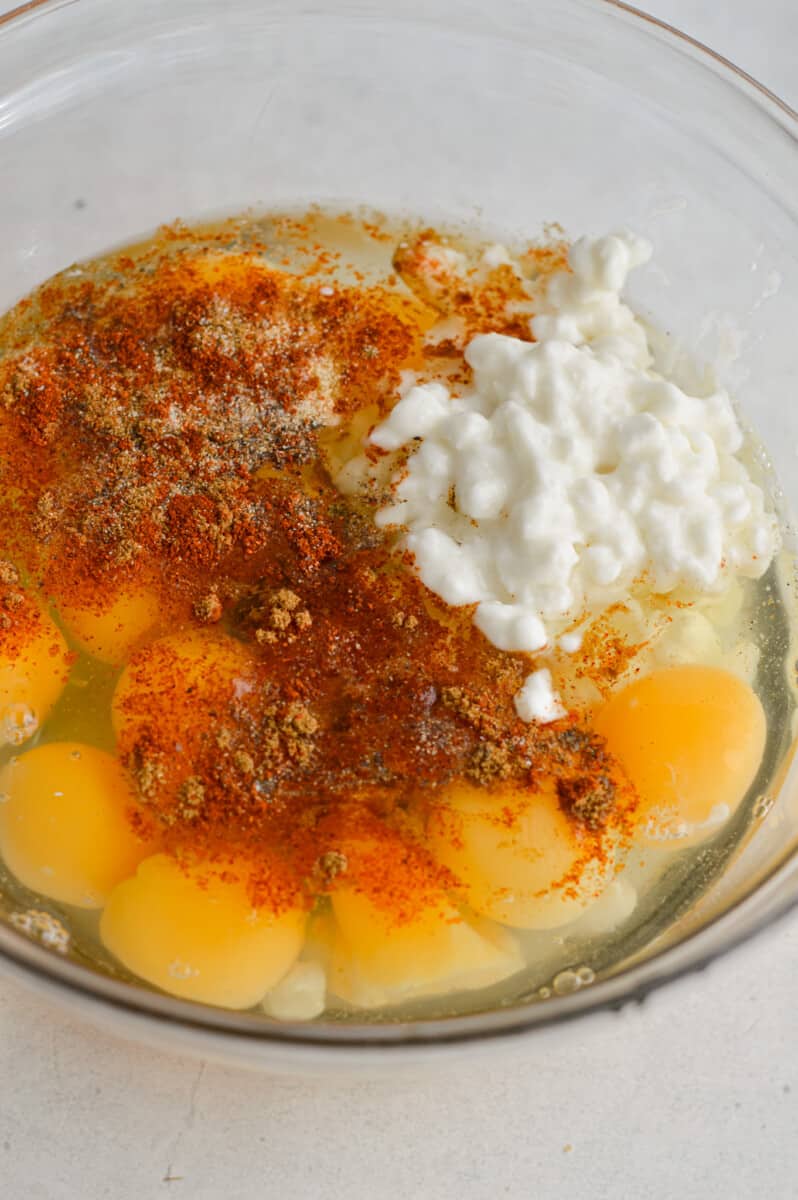 Whisking together eggs, cottage cheese, salt, black pepper, garlic powder, chili powder and ground cumin.
