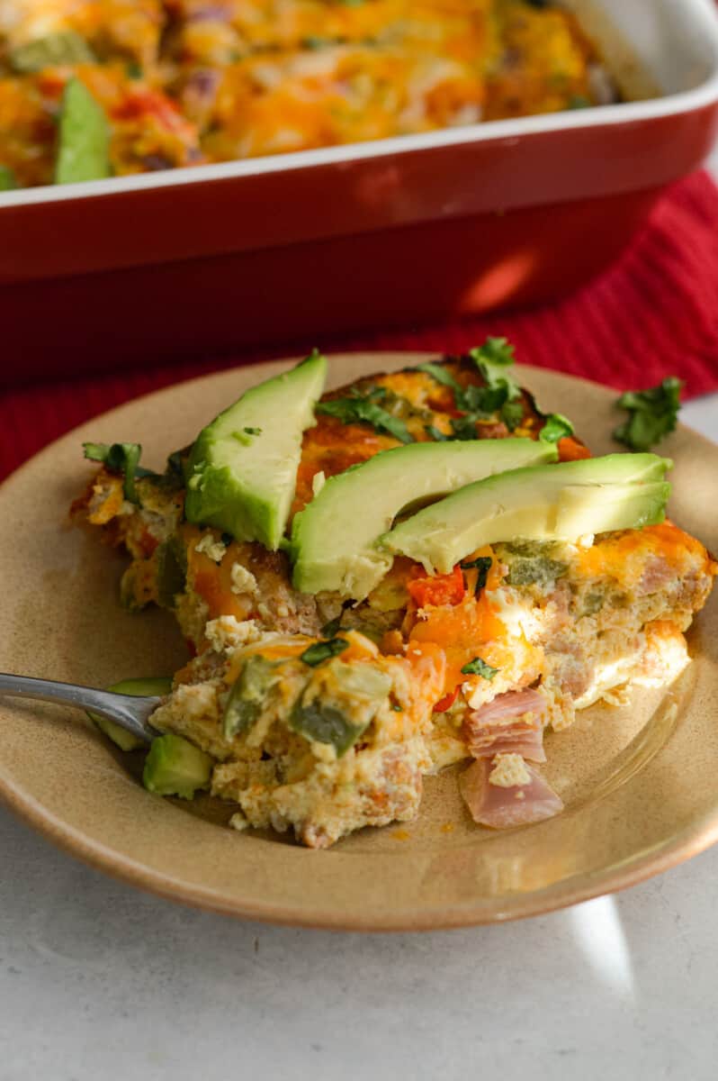 Plate of chorizo, egg & green chili breakfast casserole topped with avocado.