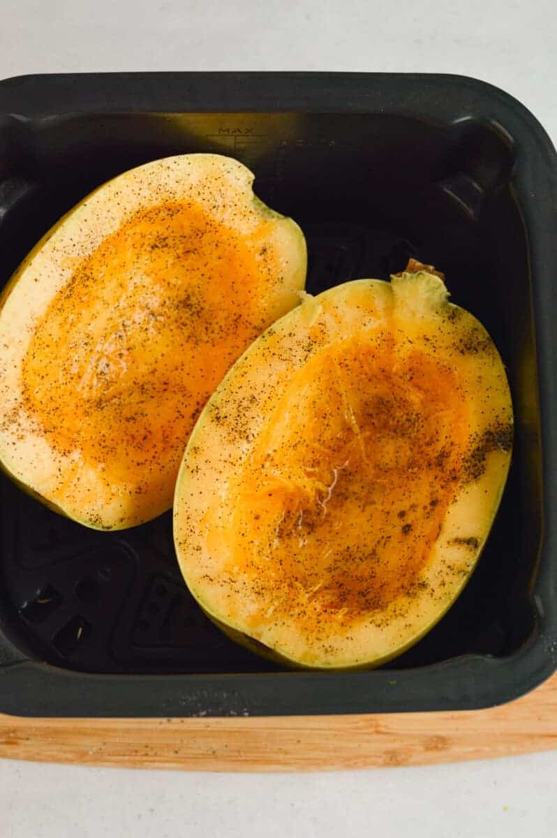 Two spaghetti squash halves in an air fryer.
