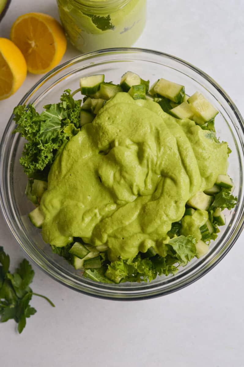 Pouring avocado green goddess dressing on salad.