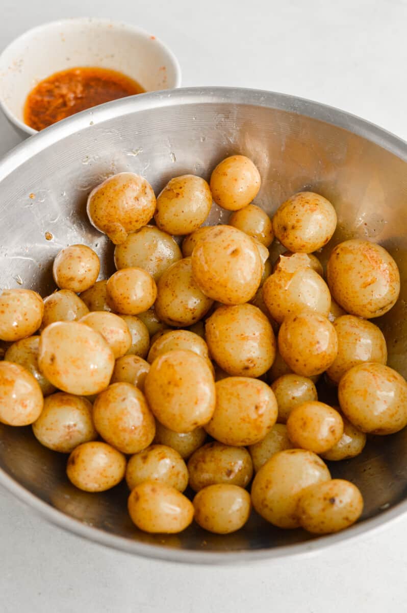 Coating baby potatoes with oil mixture.