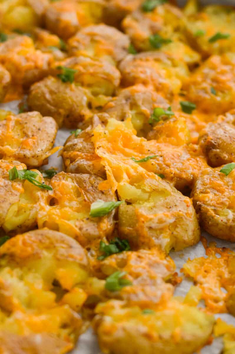 Close up of cheesy smashed potatoes topped with chives.