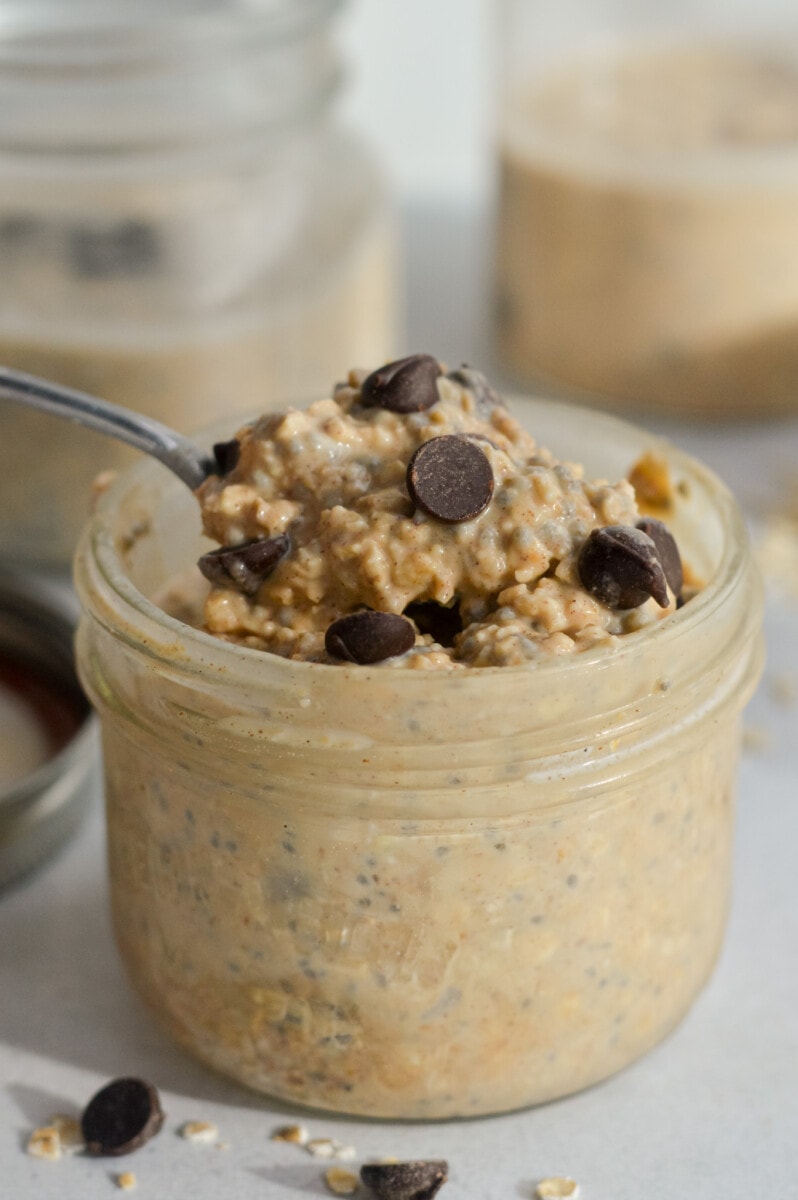 Spoon scooping cookie dough overnight oats out of a jar.