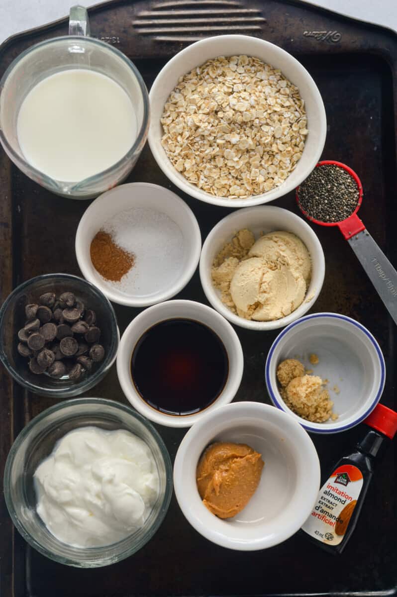 Ingredients including oats, protein powder, greek yogurt, chocolate chips, chia seeds, cinnamon, milk, brown sugar, and peanut butter.