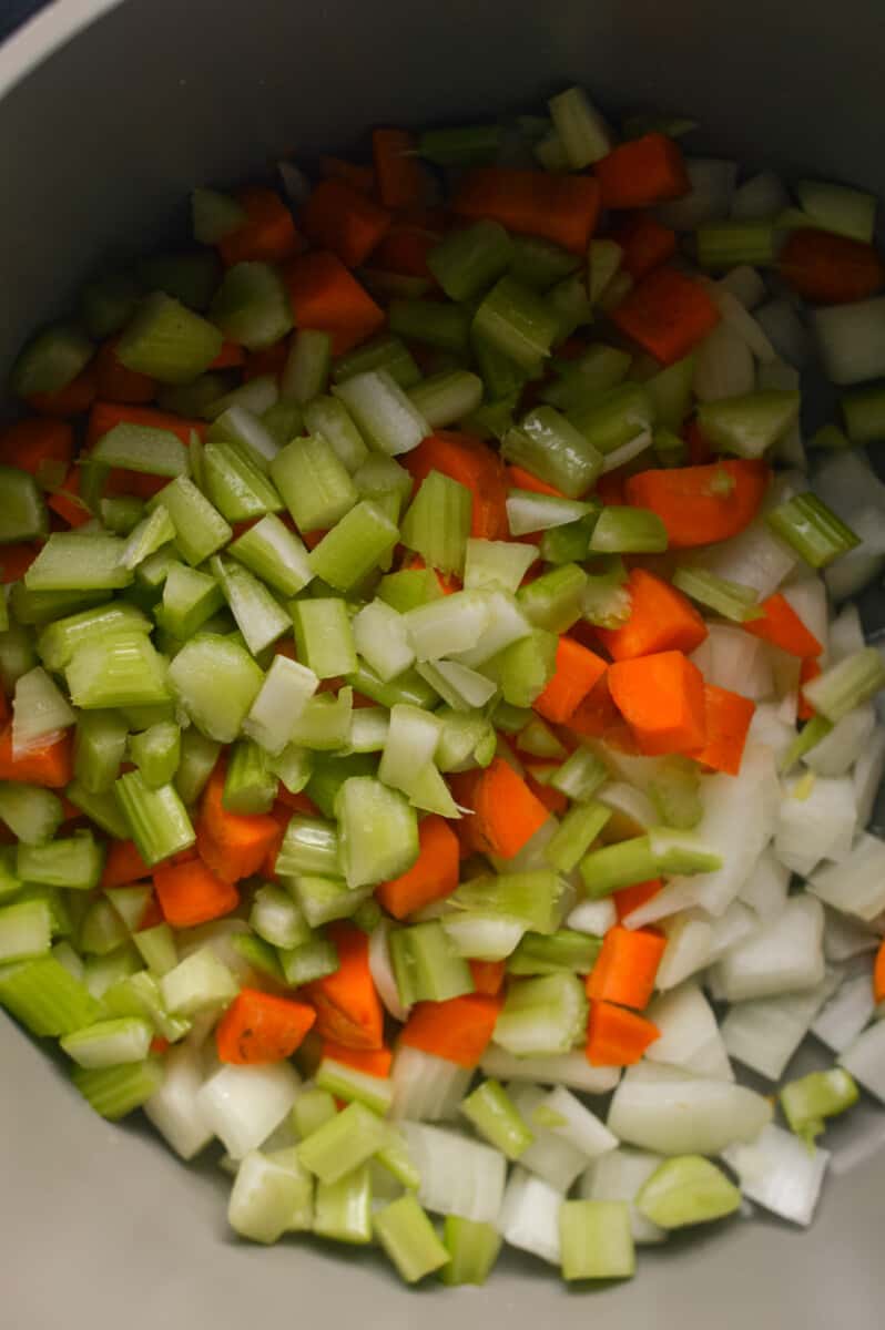 Adding diced carrots, celery and onion to a pot.