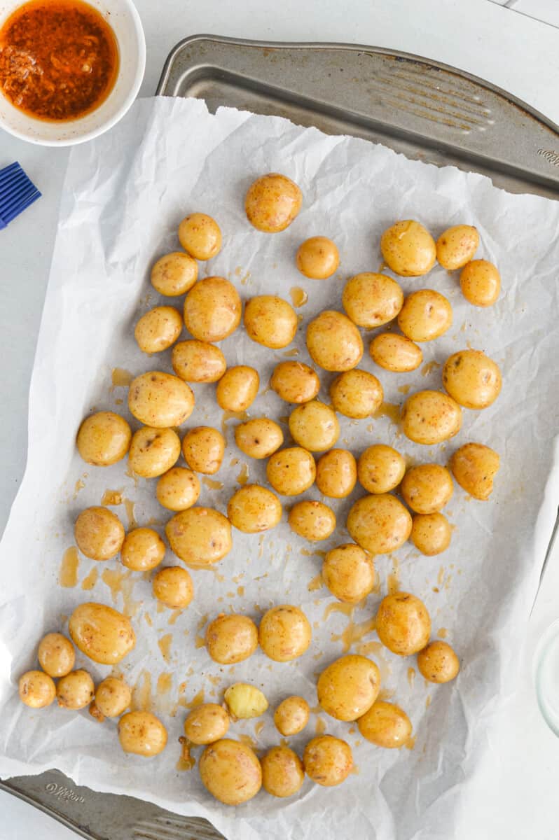 Spreading baby potatoes on lined baking tray.