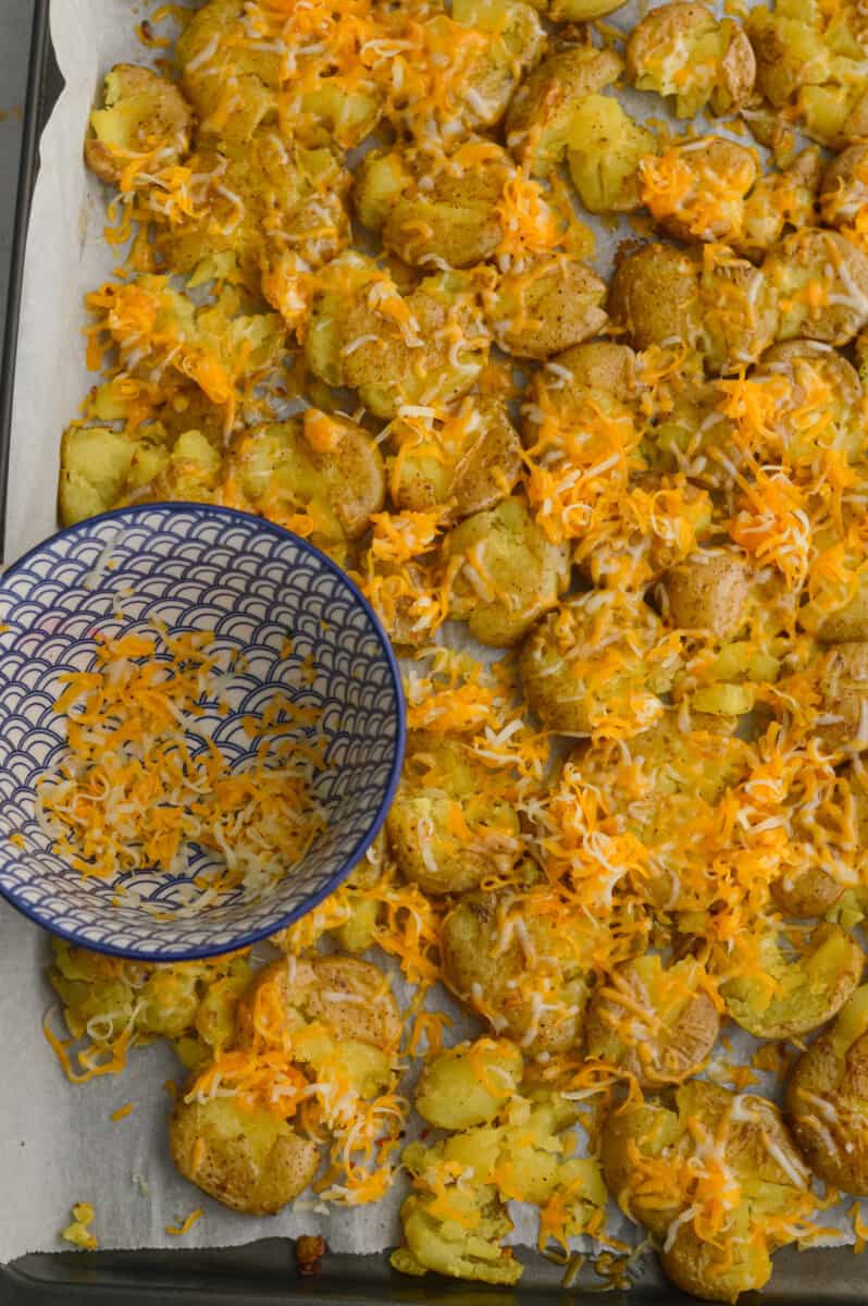 Sprinkling cheese on smashed potatoes.