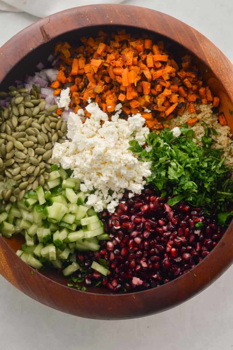 Crunchy kale winter salad with pomegranates, cucumber, pumpkin seeds, feta, parsley, sweet potato, and quinoa.